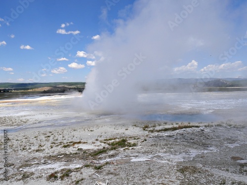 Wide shot of Clepsydra Geyser with steam shooting up at the Lower Geyser Basin, Yellowstone National Park.