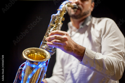 Saxofonista sobre fondo negro tocando saxofón con luces led en discoteca photo