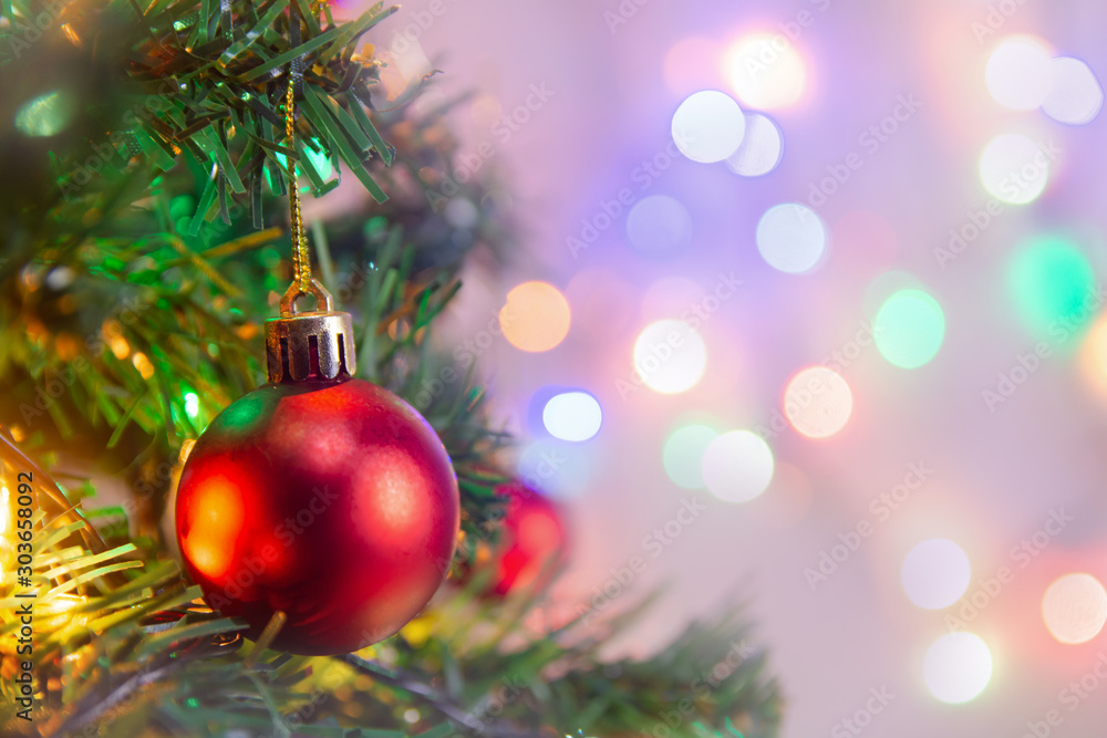Fototapeta premium Christmas decoration. Hanging red balls on pine branches Christmas tree garland and ornaments over abstract bokeh background with copy space.