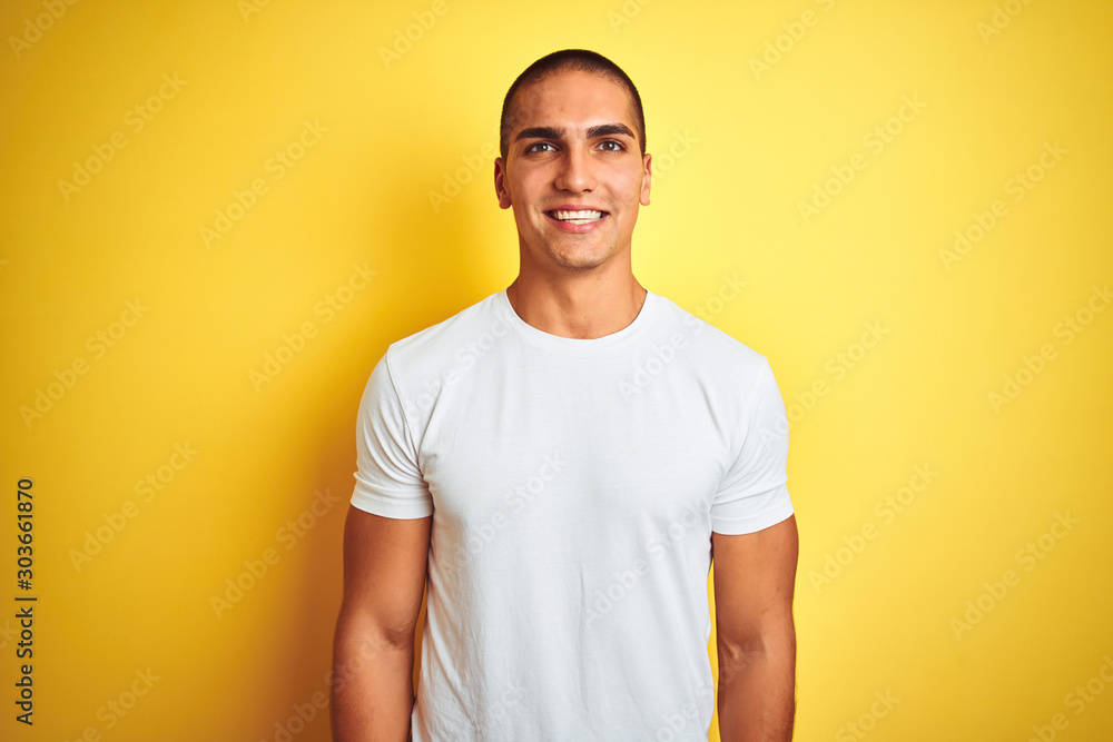 Young caucasian man wearing casual white t-shirt over yellow isolated background with a happy and cool smile on face. Lucky person. Young caucasian man wearing casual white t-shirt over yellow isolated background with a happy and cool smile on face. Lucky person.