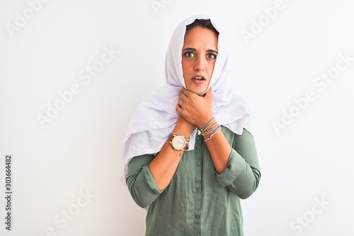 Young beautiful Arab woman wearing traditional Muslim hijab over isolated background shouting and suffocate because painful strangle. Health problem. Asphyxiate and suicide concept.