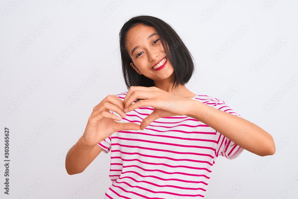 Young chinese woman wearing striped t-shirt standing over isolated white background smiling in love doing heart symbol shape with hands. Romantic concept. Young chinese woman wearing striped t-shirt standing over isolated white background smiling in love doing heart symbol shape with hands. Romantic concept.