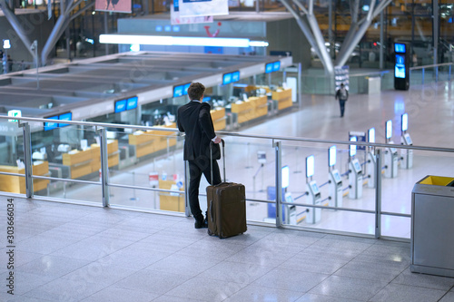 Wallpaper Mural Back of young businessman standing inside the airport with his baggage looking down on the departure lounge Torontodigital.ca