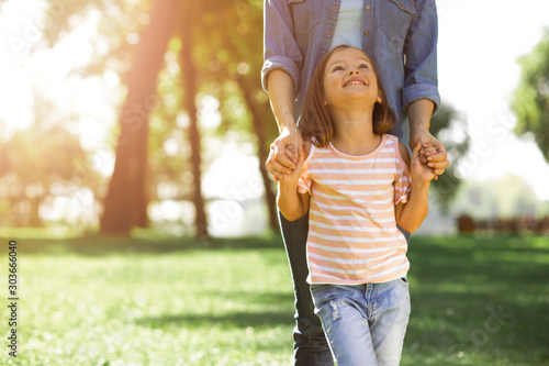 smiling girl looking up at her mother in the park, cropped shot