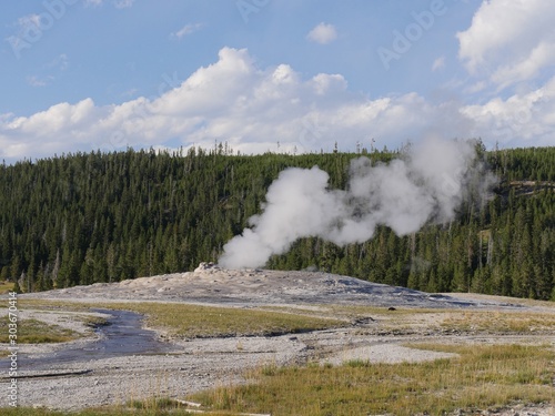 Old Faithful Geyser with the pressure of steam and scalding water spurt slowing down after an early morning eruption at Yellowstone National Park.