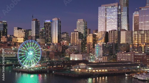 Aerial: Flying over the Seattle city skyline, Elliott Bay waterfront & Ferris wheel at sunset. Seattle, Washington, USA. 03 November 2019 photo
