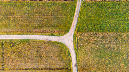 Drop down view of dirt road T-junction surrounded with fields. photo