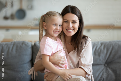Photos Portrait of happy pretty little girl sitting on mommys lap.