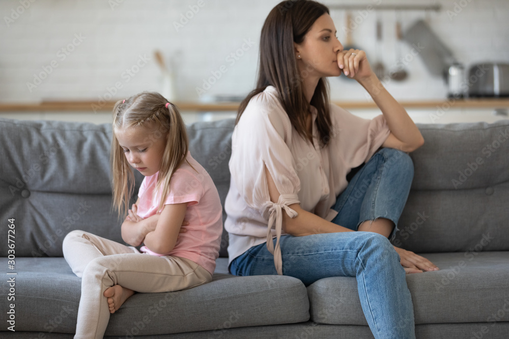 Upset girl sitting back to back with disappointed mother. Upset girl sitting back to back with disappointed mother.