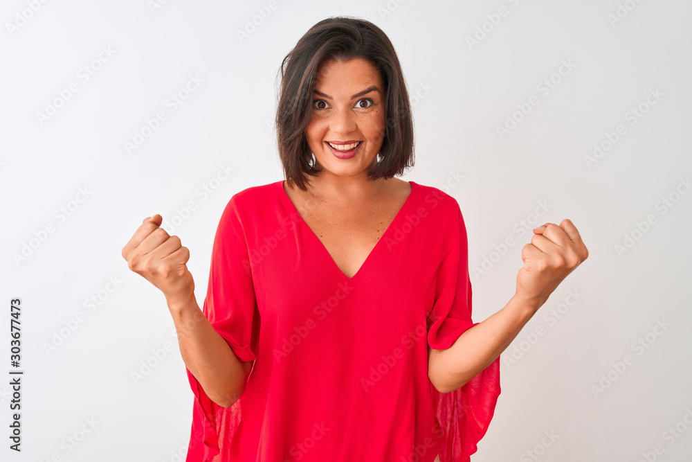 Young beautiful woman wearing red t-shirt standing over isolated white background celebrating surprised and amazed for success with arms raised and open eyes. Winner concept. Young beautiful woman wearing red t-shirt standing over isolated white background celebrating surprised and amazed for success with arms raised and open eyes. Winner concept.