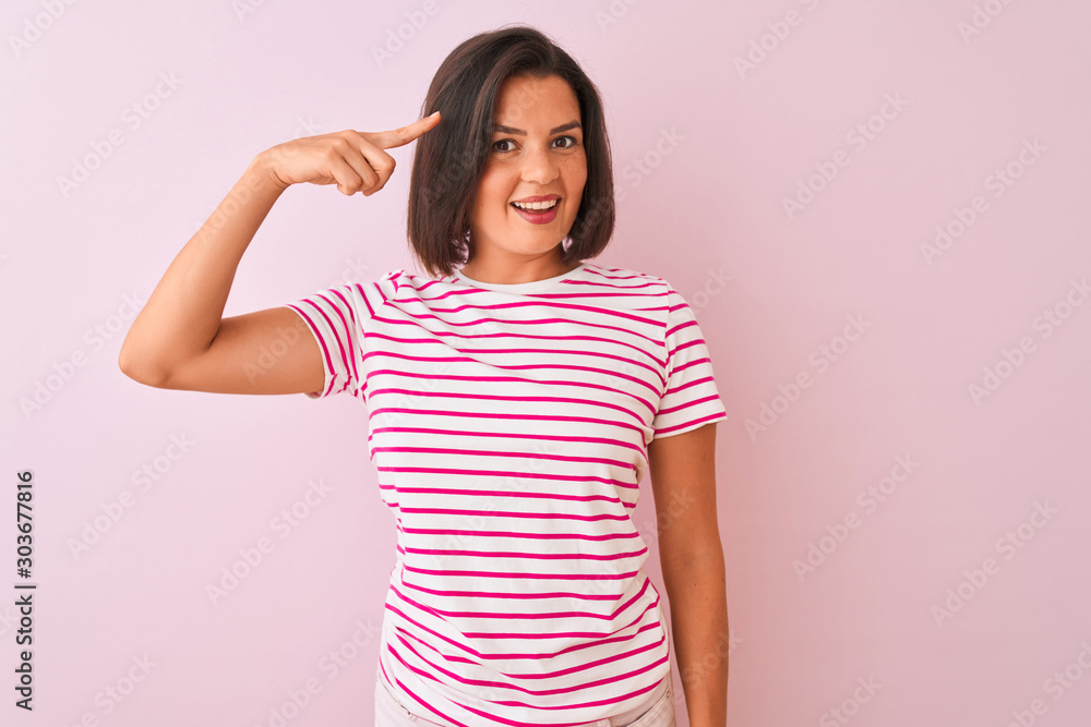 Young beautiful woman wearing striped t-shirt standing over isolated pink background Smiling pointing to head with one finger, great idea or thought, good memory Young beautiful woman wearing striped t-shirt standing over isolated pink background Smiling pointing to head with one finger, great idea or thought, good memory