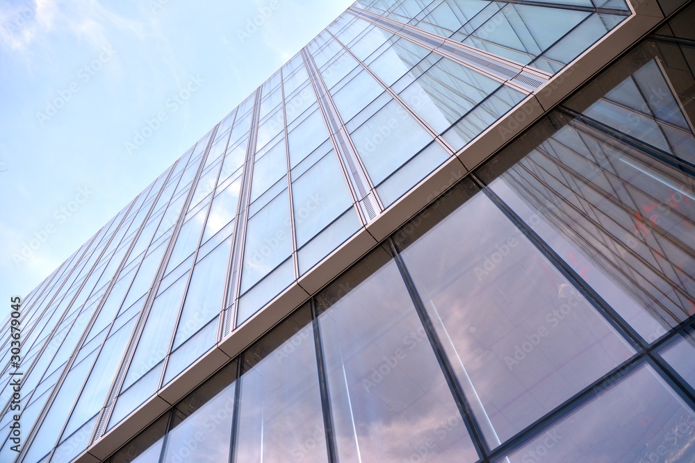 Obraz premium Modern office building wall made of steel and glass with blue sky