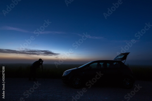 photographer with the car in the field, night, backlight