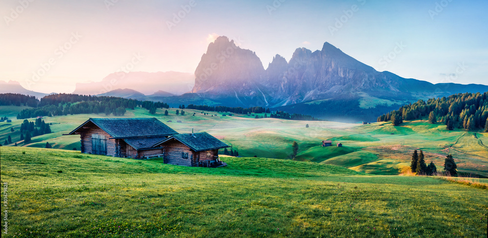 Stunning morning scene of Compaccio village with Langkofel/Sassolungo peak on background. Seiser Alm or Alpe di Siusi location, Bolzano province, Europe. Amazing summer view of Dolomiti Alps.