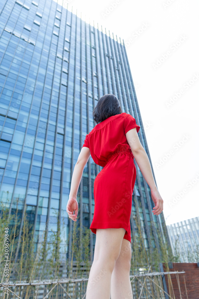 young woman dancing in red dress near office building