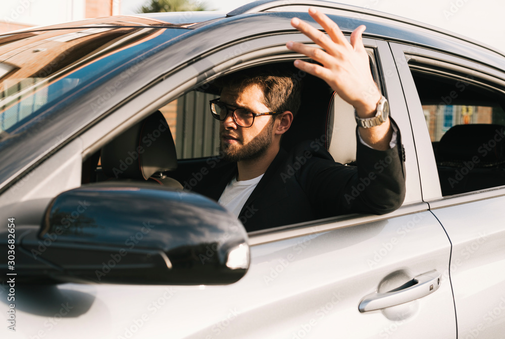 Attractive young man with a beard and glasses gets angry driving his car. Attractive young man with a beard and glasses gets angry driving his car.