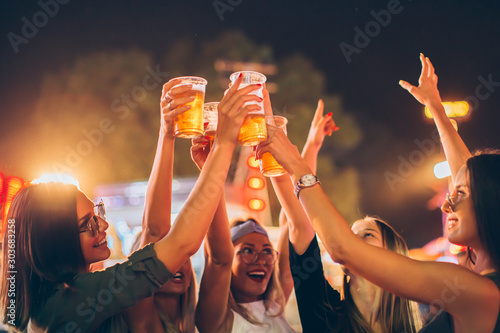Group of female friends cheering with beer in amusement park