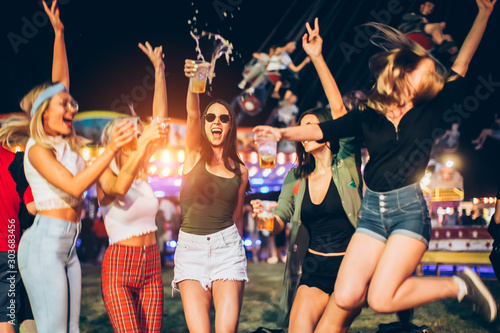 Happy group of female friends jumping and having fun at the music festival