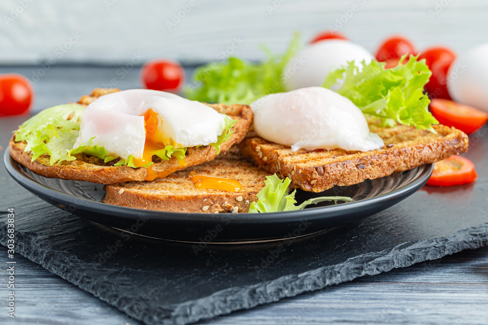 Plate with sandwiches of poached egg and fresh vegetables.