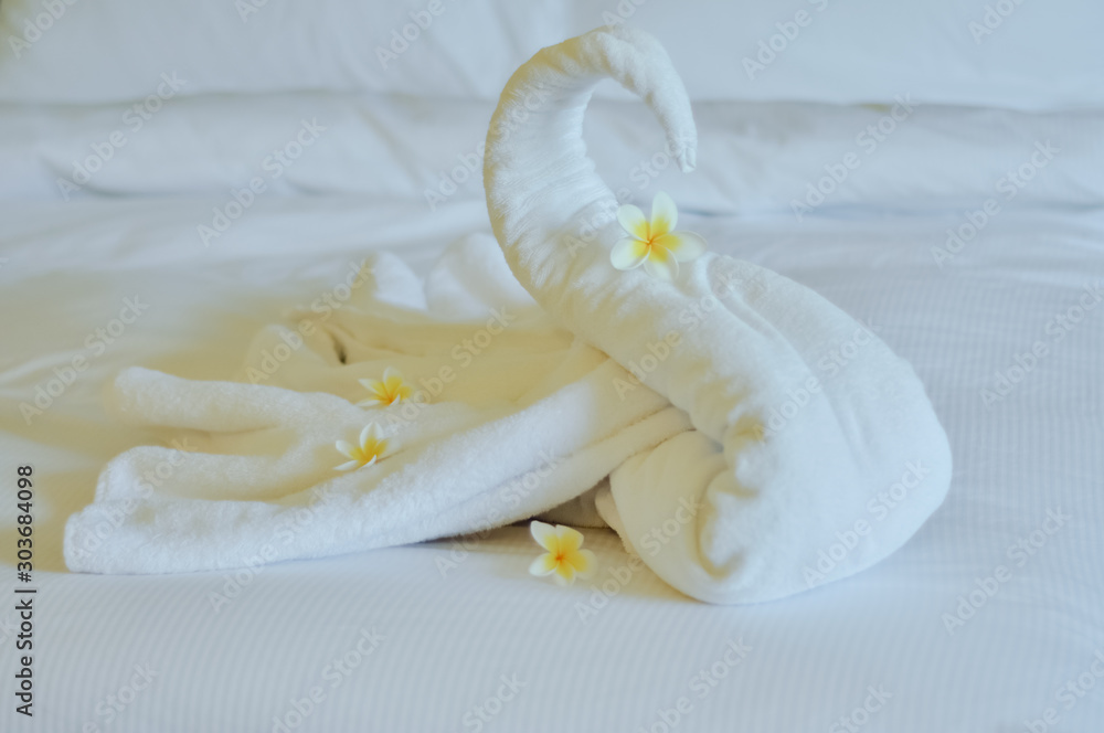 Beautiful swan from white bath towel decorate on white bed. towel swan with topical flowers - frangipani. Nice greeting from Hotel. Beautiful swan from white bath towel decorate on white bed. towel swan with topical flowers - frangipani. Nice greeting from Hotel.