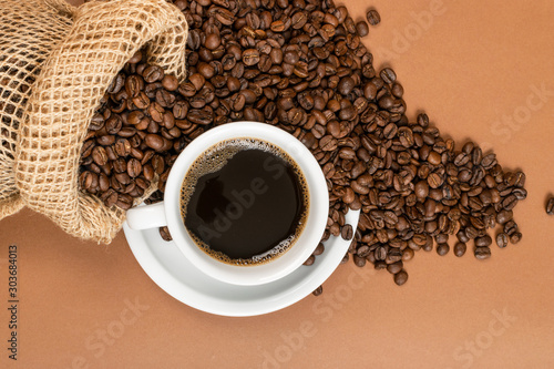 Hot coffee cup and coffee beans in burlap bag photo