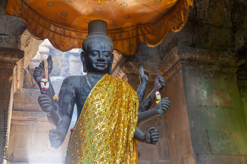 Statue of Vishnu at Angkor Wat. Standing in a nice spot which is lit from behind by the sun shining through a opeing in the ceiling. photo