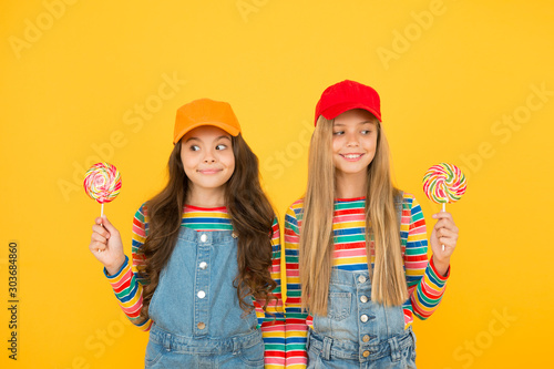 Happy childrens day. cute sisters lollipop candy. cheerful kids have party fun. school friends enjoy holiday celebration. candy shop concept. sweet life. childhood happiness. positive and friendly