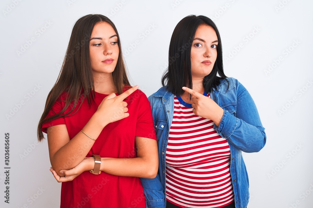 Young beautiful women wearing casual clothes standing over isolated white background Pointing with hand finger to the side showing advertisement, serious and calm face
