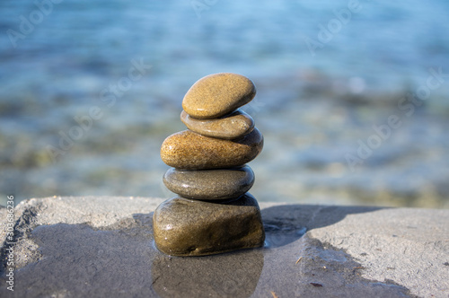 Five stones cairn tower  rock zen sculpture  brown beige pebbles and sea light blue background