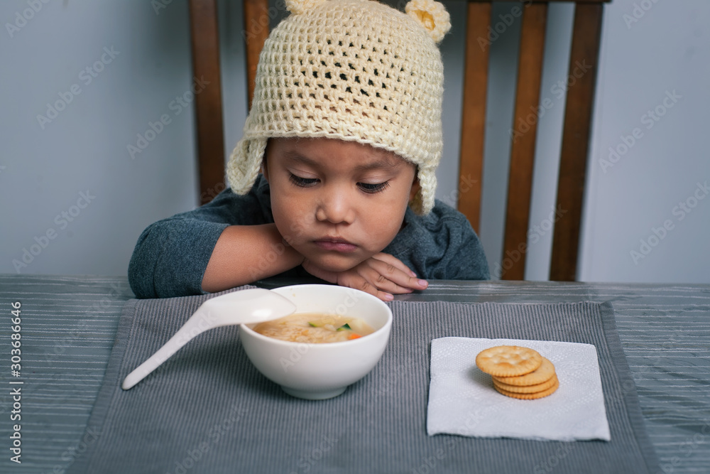 Loss of appetite for a sick toddler who is holding his sore throat with his hand and is staring