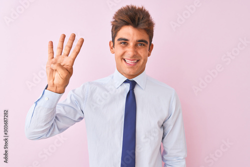 Young handsome businessman wearing shirt and tie standing over isolated pink background showing and pointing up with fingers number four while smiling confident and happy.