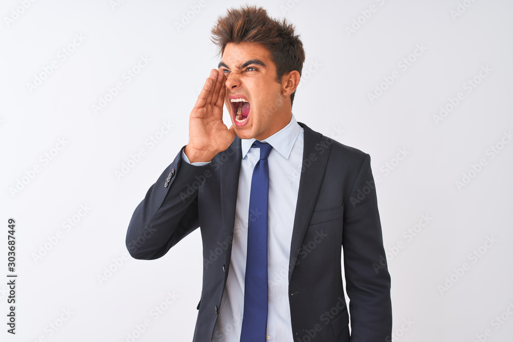 Young handsome businessman wearing suit standing over isolated white background shouting and screaming loud to side with hand on mouth. Communication concept. Young handsome businessman wearing suit standing over isolated white background shouting and screaming loud to side with hand on mouth. Communication concept.