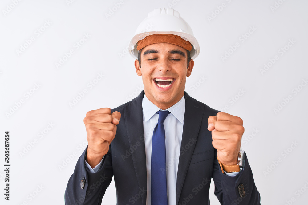 Young handsome architect man wearing suit and helmet over isolated white background excited for success with arms raised and eyes closed celebrating victory smiling. Winner concept. Young handsome architect man wearing suit and helmet over isolated white background excited for success with arms raised and eyes closed celebrating victory smiling. Winner concept.