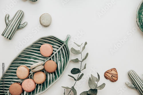 Macaroons on a plate next to catci decorations and a eucalyptus branch photo