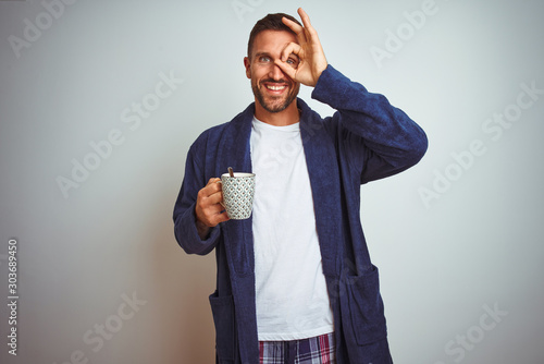 Man wearing comfortable pajamas and robe drinking cup of coffee over isolated background with a confident expression on smart face thinking serious