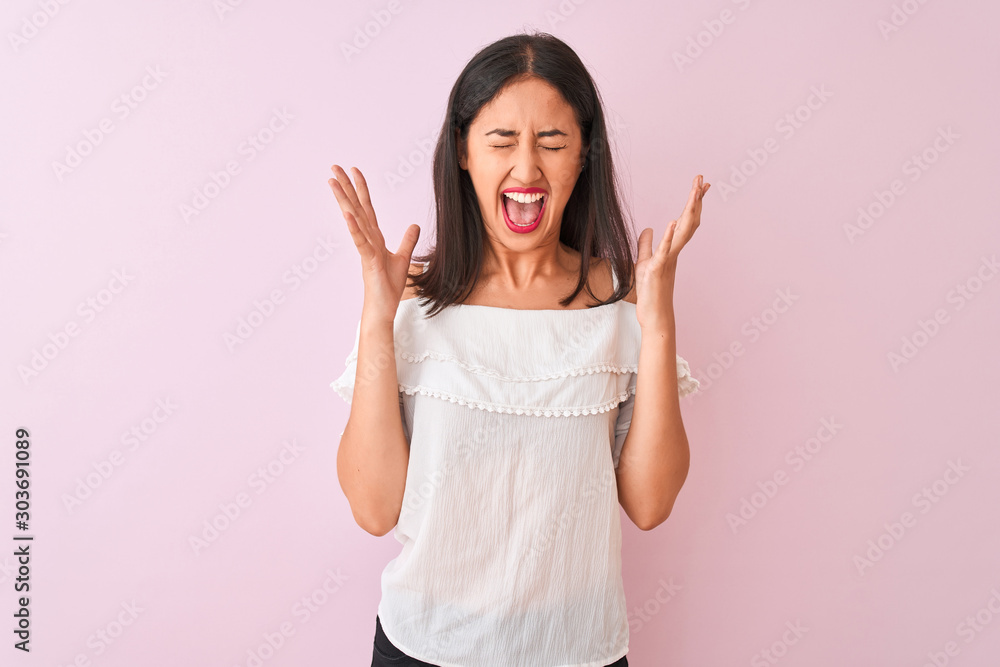 Beautiful chinese woman wearing white t-shirt standing over isolated pink background celebrating mad and crazy for success with arms raised and closed eyes screaming excited. Winner concept Beautiful chinese woman wearing white t-shirt standing over isolated pink background celebrating mad and crazy for success with arms raised and closed eyes screaming excited. Winner concept