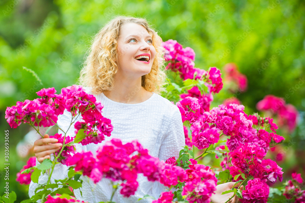 Beautiful woman with spring blooming rose flowers. Young smiling girl enjoys pink rose flowers. Summer time. Happy woman walking at rose garden. Pink rosebush blooming. Beautiful woman with spring blooming rose flowers. Young smiling girl enjoys pink rose flowers. Summer time. Happy woman walking at rose garden. Pink rosebush blooming.