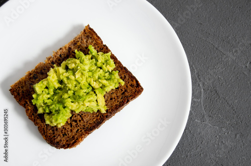 Rustic toast with smash avocado and cereal bread on plate and concrete top view