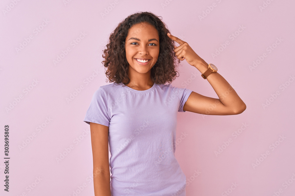 Young brazilian woman wearing t-shirt standing over isolated pink background Smiling pointing to head with one finger, great idea or thought, good memory Young brazilian woman wearing t-shirt standing over isolated pink background Smiling pointing to head with one finger, great idea or thought, good memory