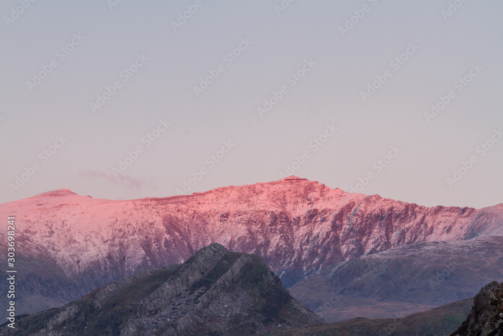 Peak of Mount Snowdon lit by sunset
