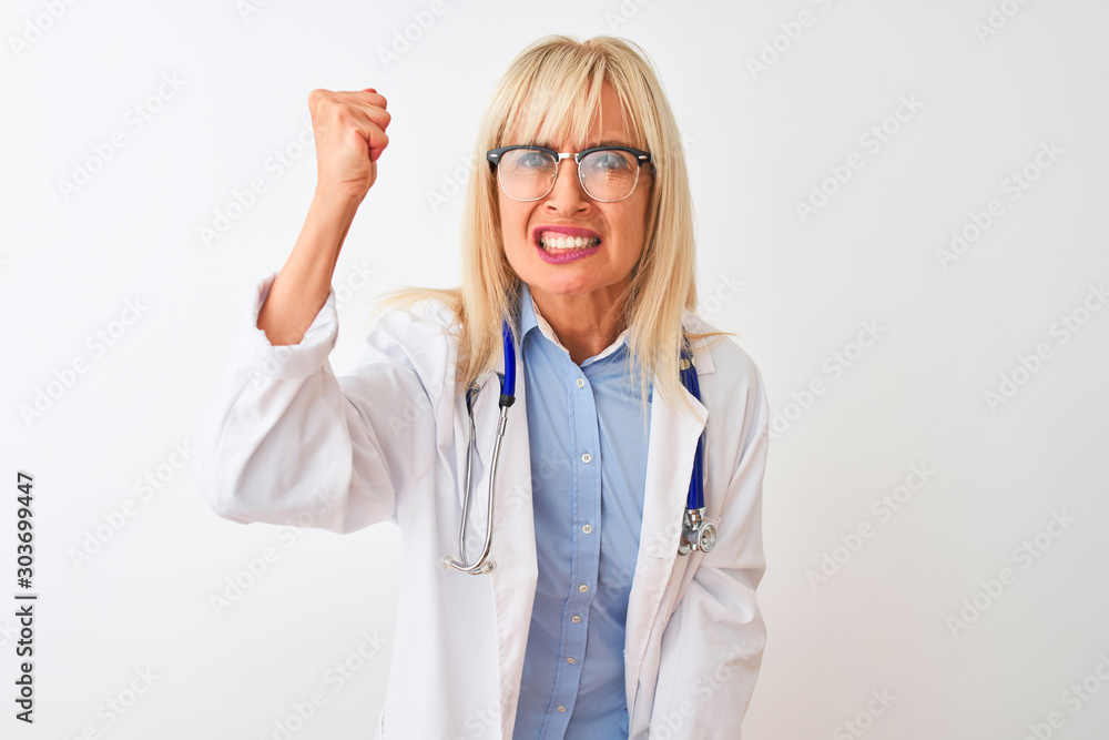 Middle age doctor woman wearing glasses and stethoscope over isolated white background angry and mad raising fist frustrated and furious while shouting with anger. Rage and aggressive concept. Middle age doctor woman wearing glasses and stethoscope over isolated white background angry and mad raising fist frustrated and furious while shouting with anger. Rage and aggressive concept.