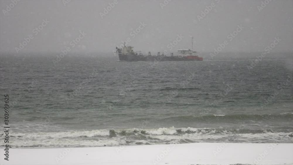 Large ship off coastline during heavy snow storm. Large ship off coastline during heavy snow storm.