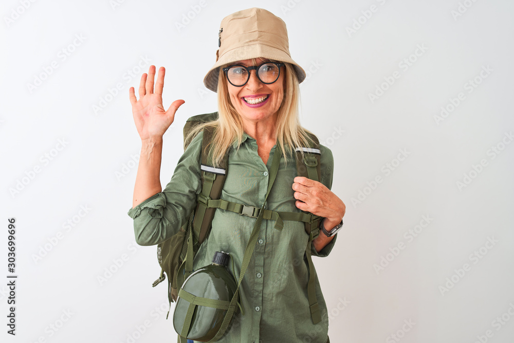 Middle age hiker woman wearing backpack hat canteen glasses over isolated white background showing and pointing up with fingers number five while smiling confident and happy. Middle age hiker woman wearing backpack hat canteen glasses over isolated white background showing and pointing up with fingers number five while smiling confident and happy.