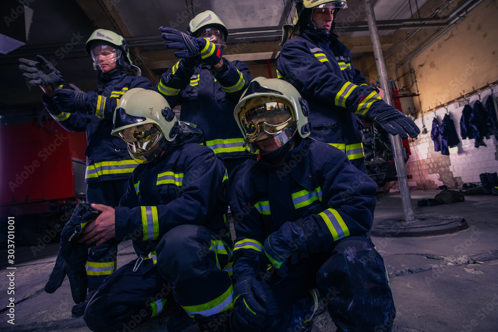 Portrait of group firefighters in front of firetruck inside the fire station Portrait of group firefighters in front of firetruck inside the fire station