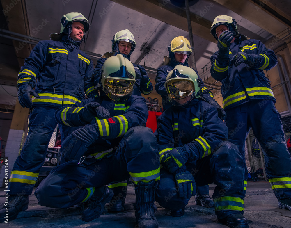 Portrait of group firefighters in front of firetruck inside the fire station Portrait of group firefighters in front of firetruck inside the fire station