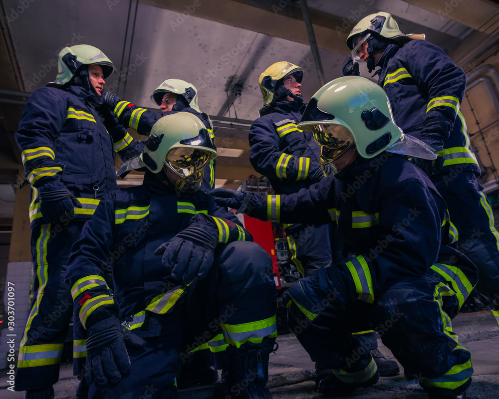Portrait of group firefighters in front of firetruck inside the fire station Portrait of group firefighters in front of firetruck inside the fire station