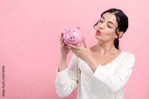 Young woman with a piggy bank on a pink background