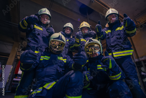 Portrait of group of firefighters wearing protective uniform inside the fire station