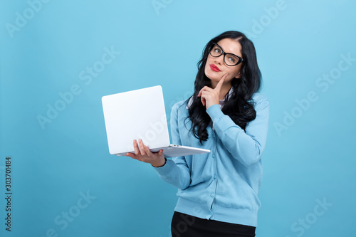 Young woman with a laptop computer in a thoughtful pose on a blue background