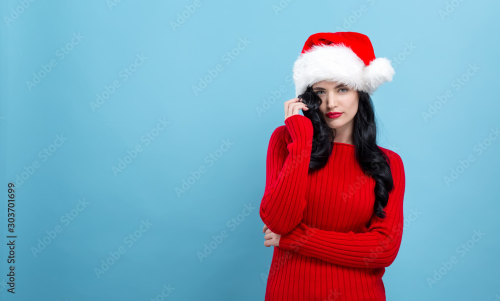 Young woman with a Santa hat on a blue background Young woman with a Santa hat on a blue background